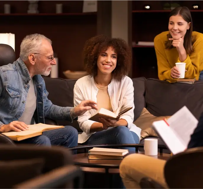 Three people leafing through a book and smiling